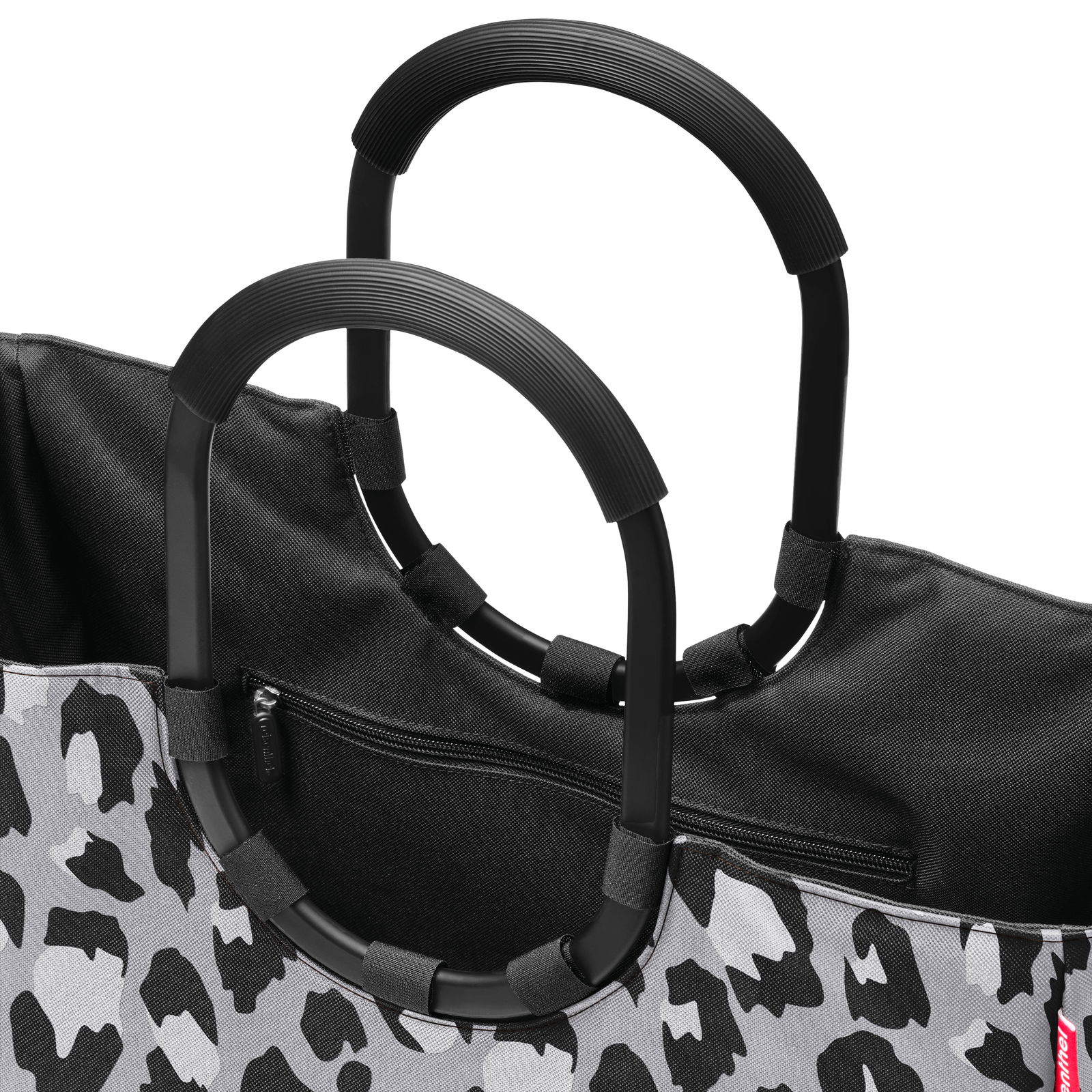 Nahaufnahme einer Tasche mit schwarzem und grauem Leopardenmuster und schwarzen Griffen, Ansicht von oben.