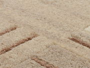 Nahaufnahme eines Wollteppichs mit beigem und braunem Muster, von oben betrachtet.