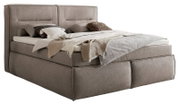 Boxspringbett in seitlicher Perspektive mit grauem Stoffbezug, dekoriert mit Kissen und Decken.