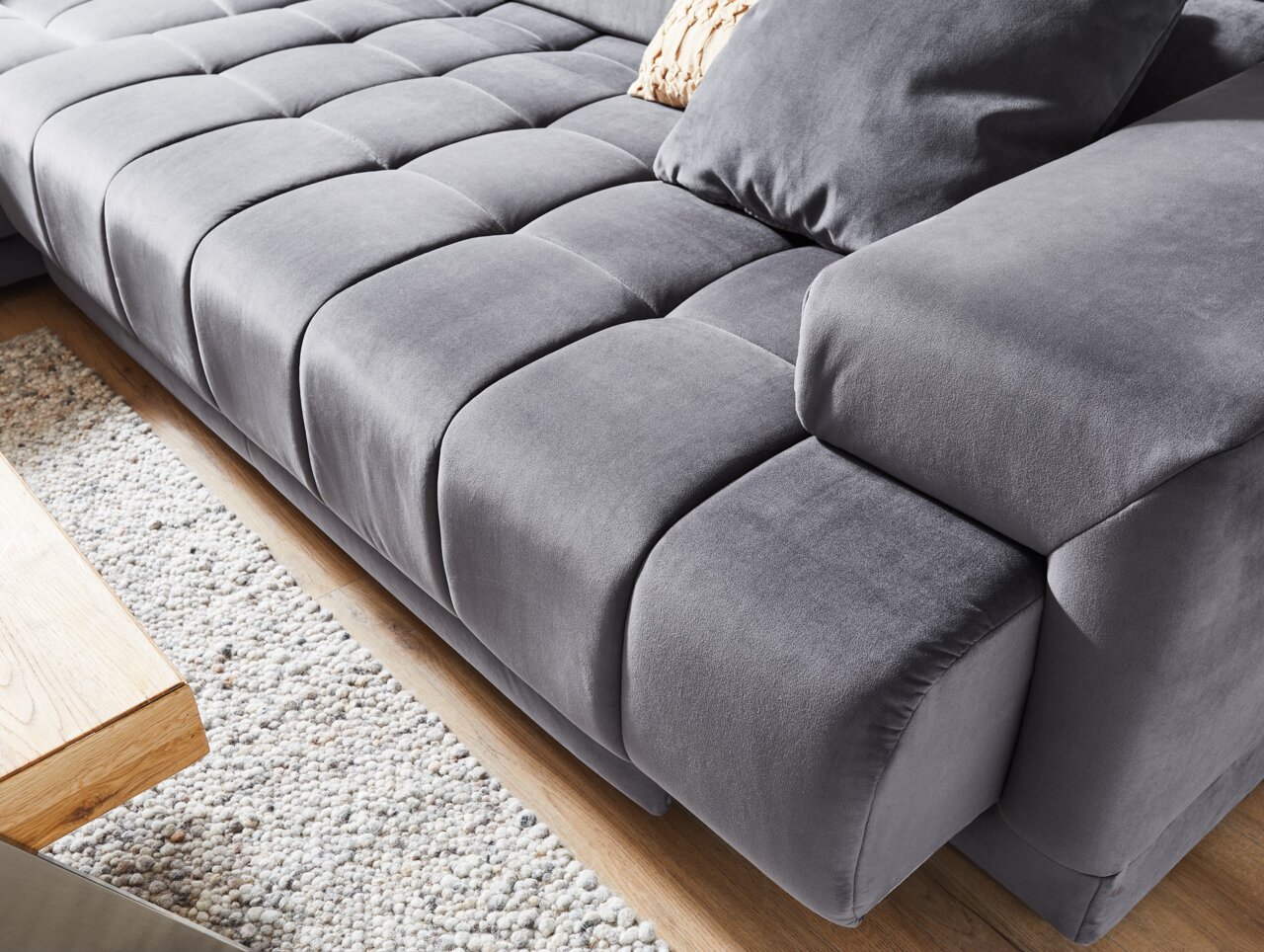 Graue Polsterrundecke in Nahaufnahme, Perspektive von schräg oben, zeigt die weiche Textur und das moderne Design.