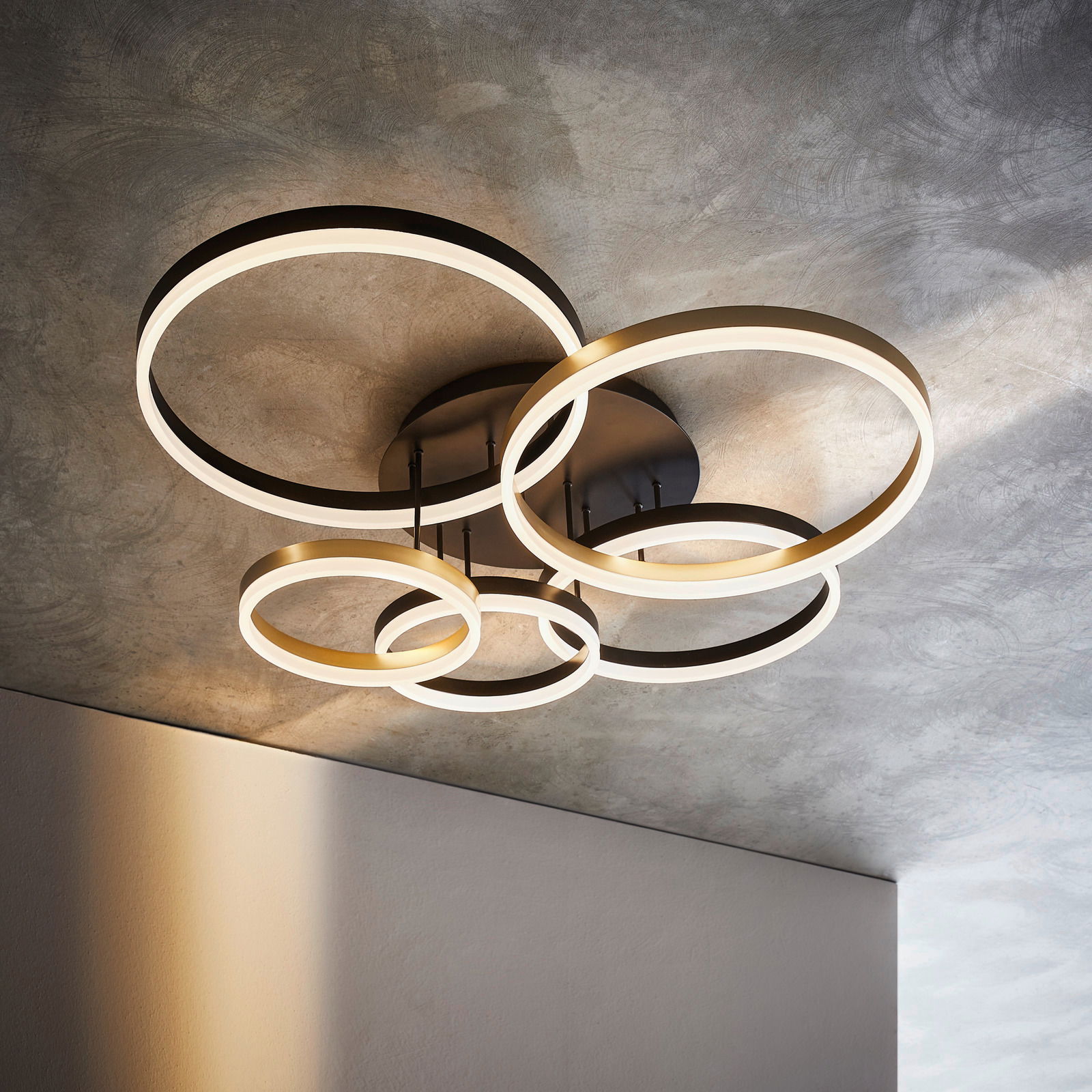 Moderne LED-Deckenleuchte mit mehreren leuchtenden Ringen, von unten betrachtet.