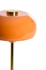 Nahaufnahme einer Tischleuchte mit orangefarbenem, glänzendem Schirm und goldenem Ständer, seitliche Perspektive.