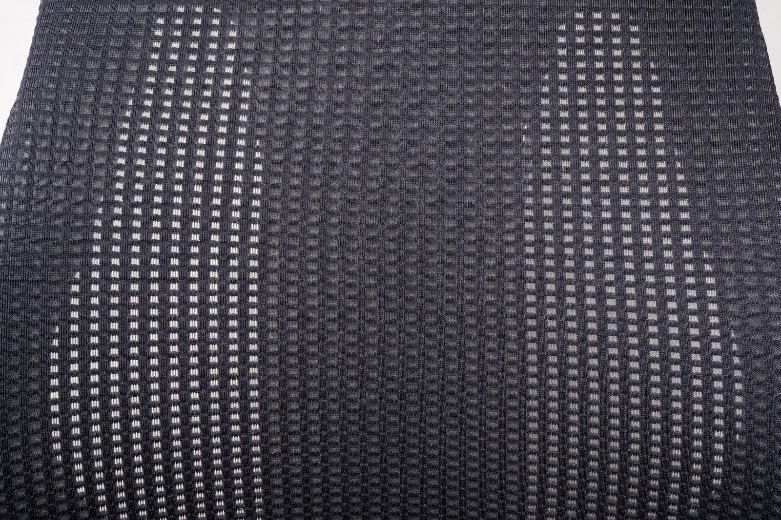 Nahaufnahme der Rückenlehne eines Drehstuhls mit grauem, gitterartigem Stoffmuster, von vorne betrachtet.