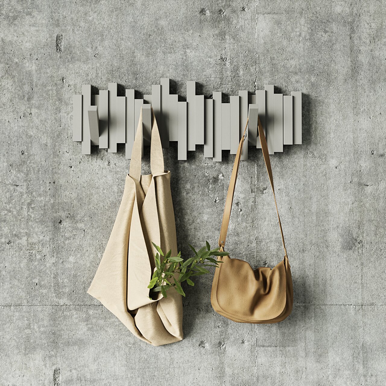 Moderne Wandgarderobe mit geometrischem Design, frontal an einer Betonwand montiert, mit zwei Taschen daran hängend.