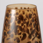 Nahaufnahme eines Weinglases mit braunem, gepunktetem Muster auf transparentem Hintergrund, seitliche Perspektive.