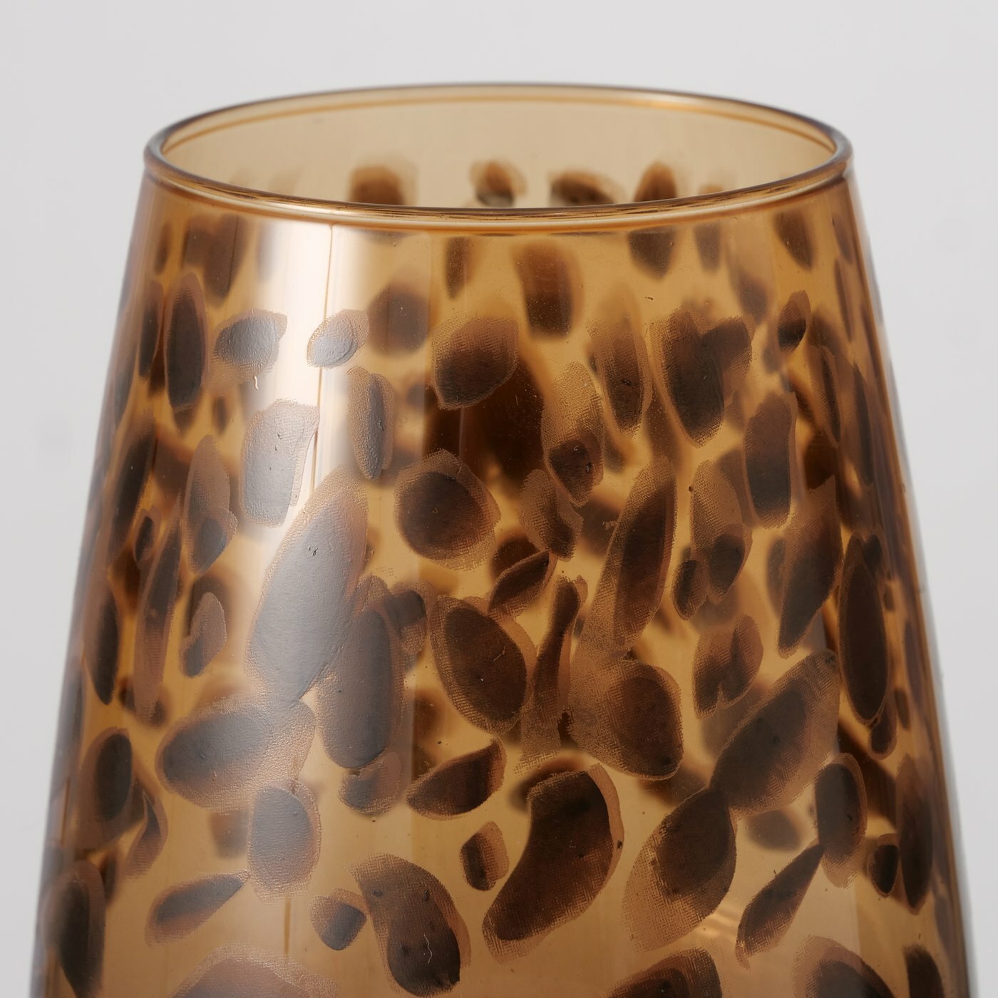 Nahaufnahme eines Weinglases mit braunem, gepunktetem Muster auf transparentem Hintergrund, seitliche Perspektive.