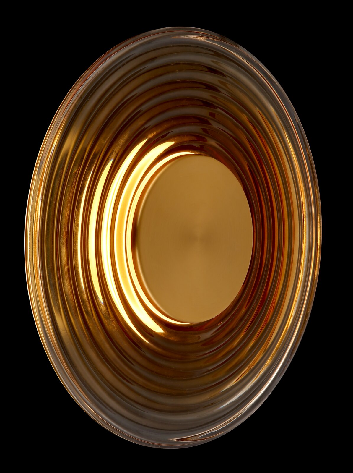 Runde, gerippte Schale aus bernsteinfarbenem Glas mit cremefarbener Einlage, Draufsicht von oben vor schwarzem Hintergrund