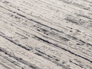 Nahaufnahme eines Designer Teppichs mit abstraktem Muster in Grautönen, von oben betrachtet.