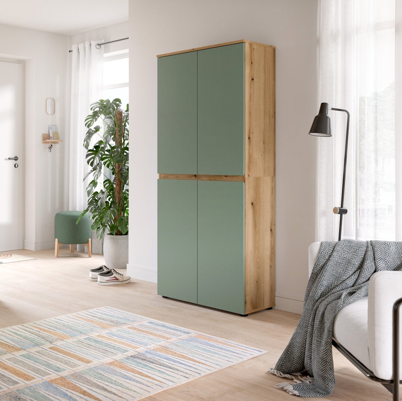 MID.YOU Universalschrank SCARPA Hoher zweitüriger Schrank mit salbeigrünen Fronten und Korpus in heller Holzoptik, im Wohnzimmer platziert; Perspektive: frontale Ansicht mit leichtem Blick von rechts.