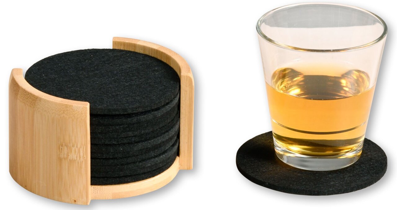 Ein Set aus schwarzen Filzuntersetzern in einem Holzhalter, mit einem Glas auf einem Untersetzer. Perspektive: seitlich.