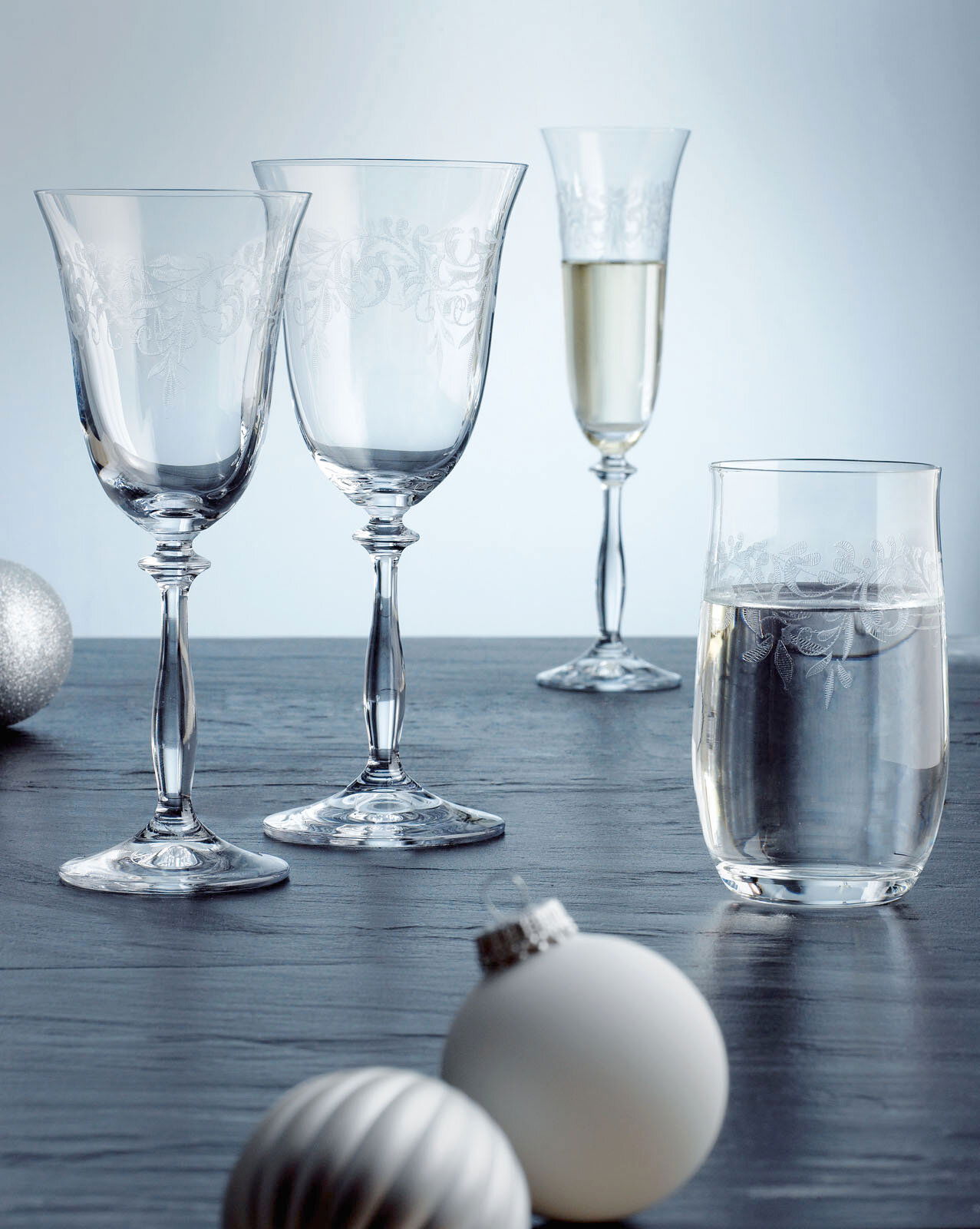 Novel Rotweinglas ROMANCE Vier elegante Gläser der Romance-Serie auf einem Tisch, darunter zwei Rotweingläser, ein Sektkelch und ein Becher, mit dekorativen Ornamenten verziert, seitliche Perspektive.
