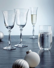 Vier elegante Gläser der Romance-Serie auf einem Tisch, darunter zwei Rotweingläser, ein Sektkelch und ein Becher, mit dekorativen Ornamenten verziert, seitliche Perspektive.