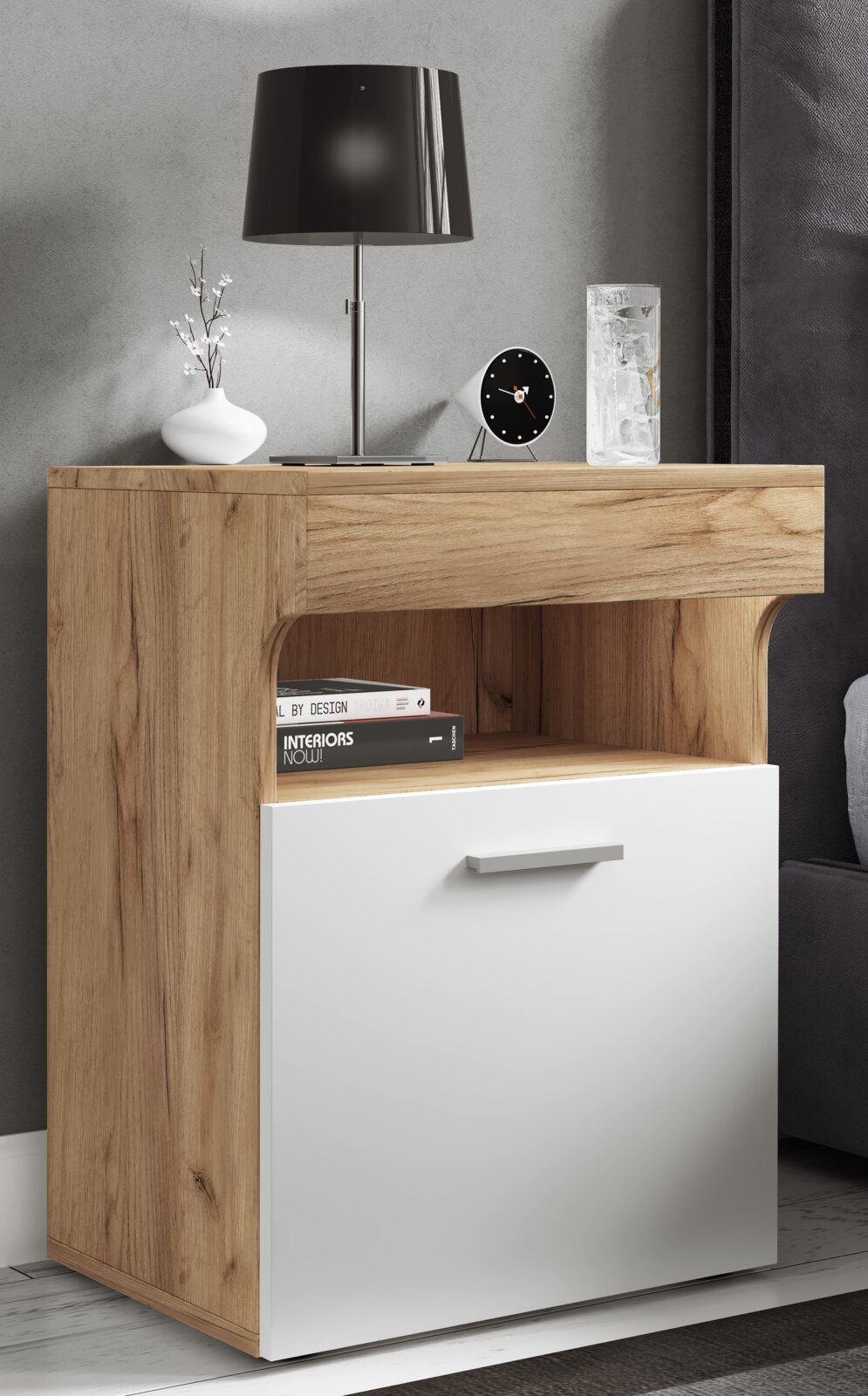 Modernes Nachttisch- bzw. Beistellschrank-Möbel in Holzoptik mit weißer Front, offenes Fach und Schublade mit Griff, darauf Lampe, Uhr und Glas; Ansicht schräg von vorn