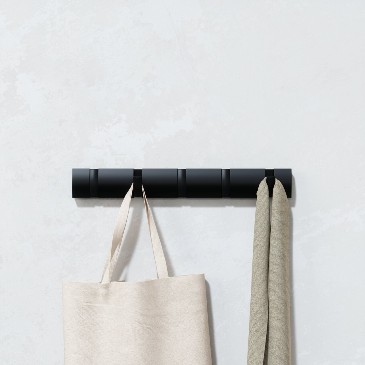 Moderne schwarze Wandgarderobe mit mehreren Haken, an der eine Tasche und ein Schal hängen, aus frontaler Perspektive.