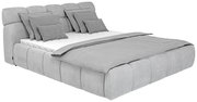 Graues Polsterbett mit mehreren Kissen und Decke, seitliche Perspektive
