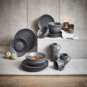 Kombiservice 20-teilig in stilvollem, dunklem Design, bestehend aus Tellern, Schalen und Tassen, präsentiert auf einer gestuften Betonoberfläche mit Kerzen im Hintergrund.