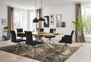 Moderner Essbereich mit einem großen Esstisch aus Holz und sechs schwarzen Sesseln auf einem gemusterten Teppich, seitliche Perspektive.