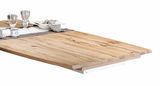 Nahaufnahme eines Esstisches aus hellem Holz mit natürlicher Maserung, gedeckt mit Geschirr und Gläsern, seitliche Perspektive.
