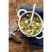 Suppentassenlöffel aus Edelstahl in einer weißen Suppenschale mit Linsensuppe, von oben fotografiert.