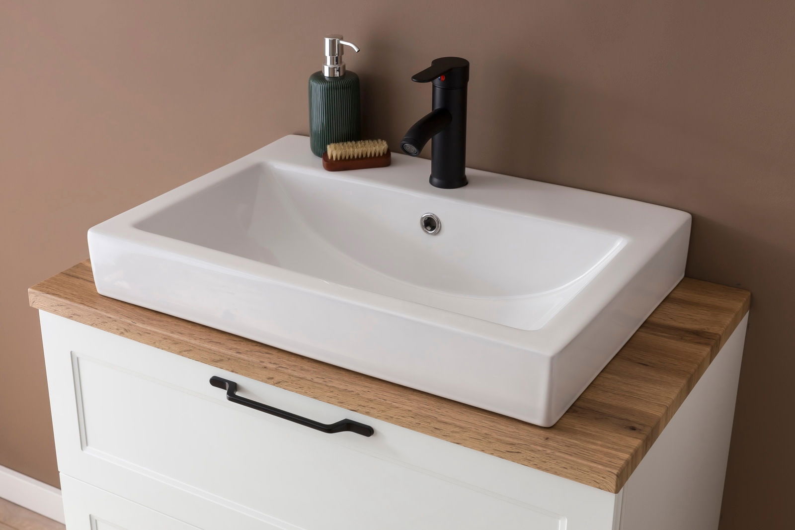 Moderner Waschtisch mit weißem Keramikbecken, schwarzer Armatur und Holzplatte, aus der Vogelperspektive fotografiert.