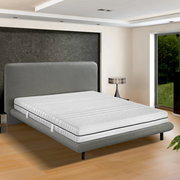 Kaltschaummatratze H2 auf einem modernen grauen Bettgestell in einem hellen Schlafzimmer, seitliche Perspektive