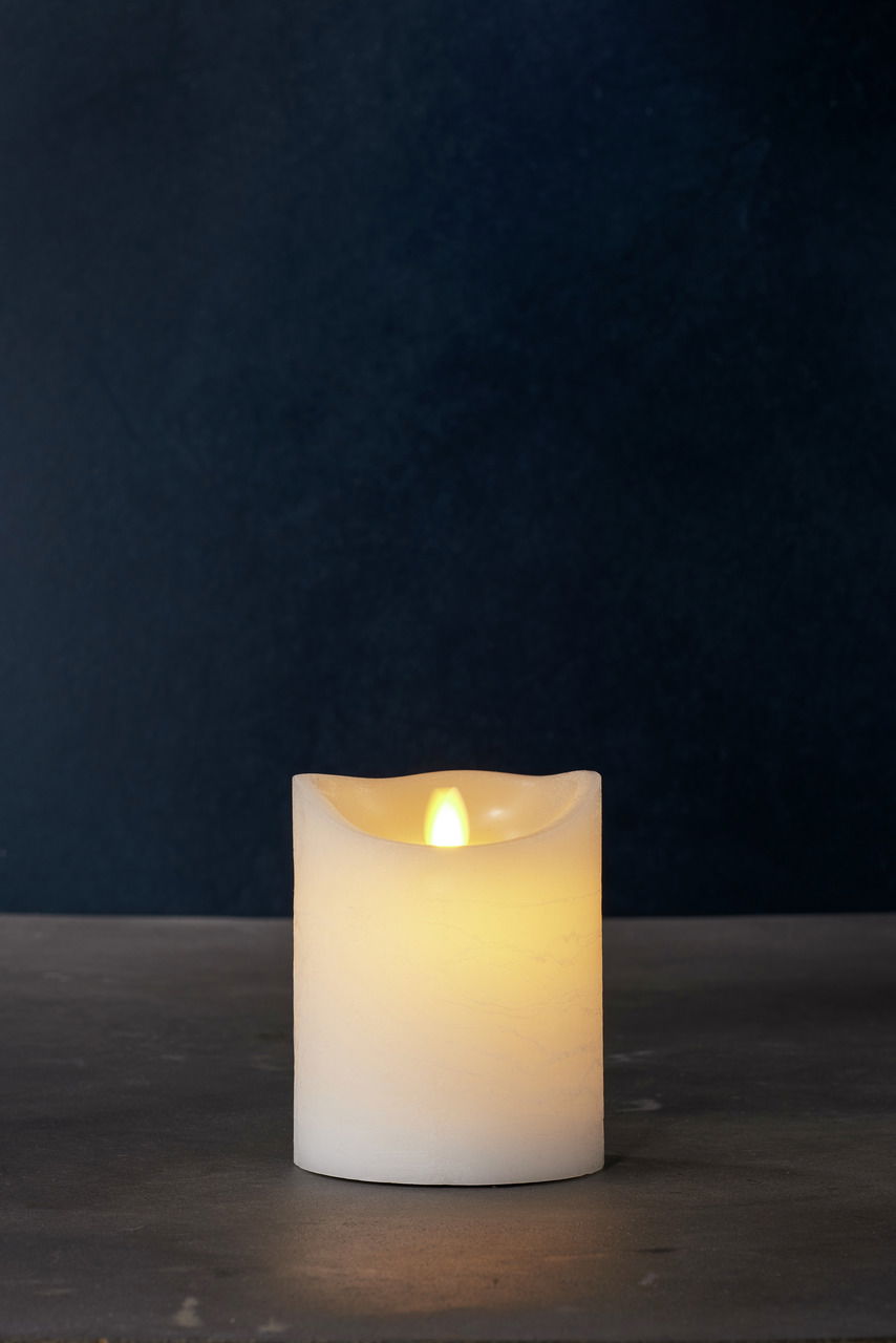 Weiße LED-Kerze mit flackerndem Licht, frontal auf einem dunklen Hintergrund fotografiert.
