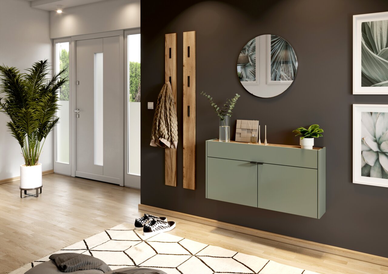 MID.YOU Hängeschuhschrank breit AMECA Moderner Eingangsbereich mit einem hängenden Schuhschrank in Salbeigrün, einem runden Spiegel und zwei Holzgarderobenleisten. Perspektive von der Seite.