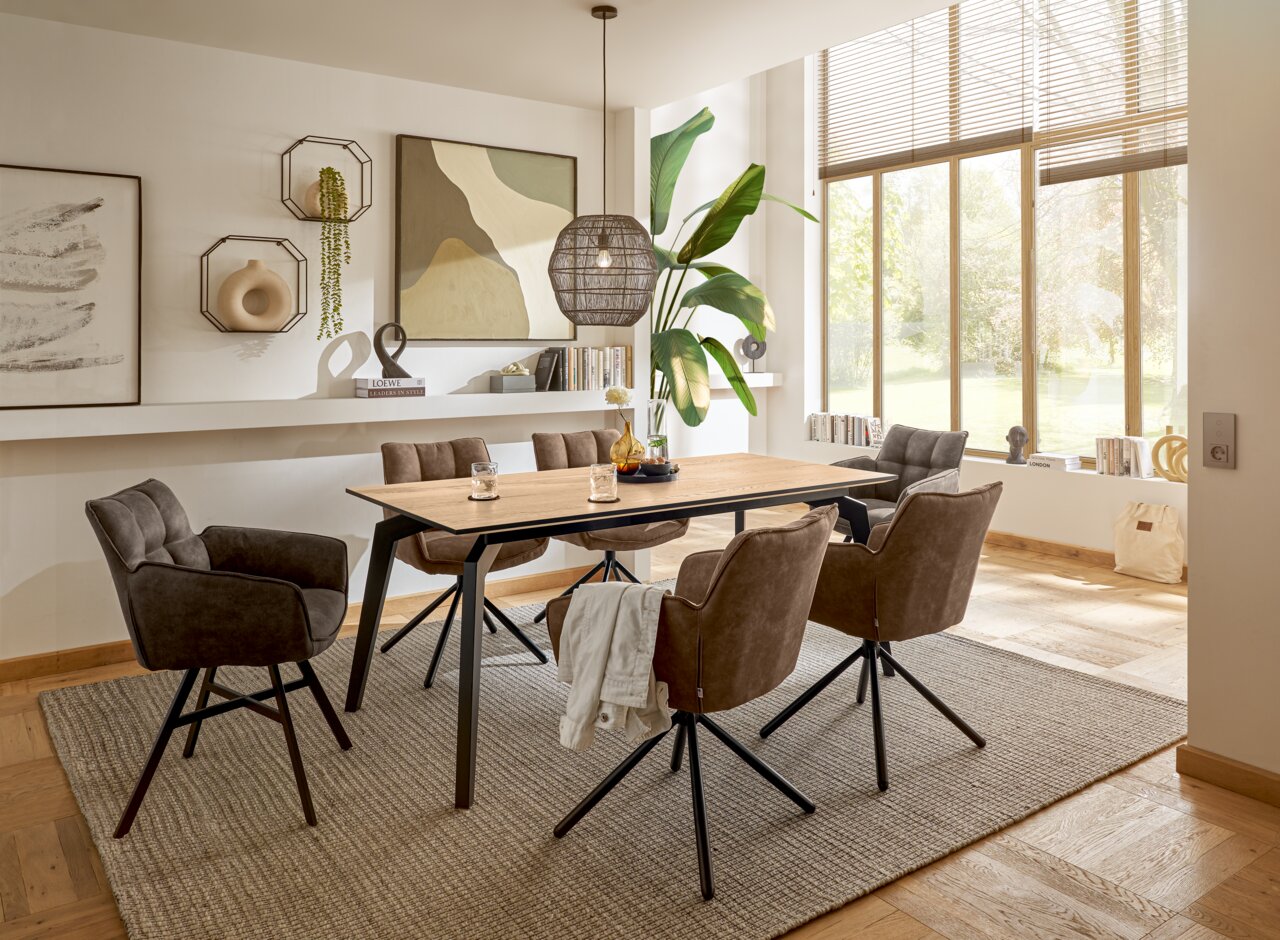 Moderner Esstisch KENT von Set one by Musterring in einem stilvollen Esszimmer, umgeben von sechs gepolsterten Stühlen, mit Blick auf große Fenster und dekorative Wandkunst.