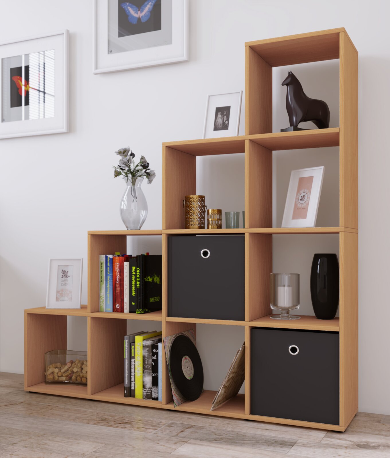 Modernes, offenes Stufenregal aus hellem Holz mit mehreren Fächern, teils mit schwarzen Boxen, dekoriert mit Büchern und Vasen; Ansicht schräg von vorn.