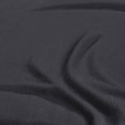 Nahaufnahme eines dunkelgrauen Spannbetttuchs mit weicher Textur, das in Falten gelegt ist.