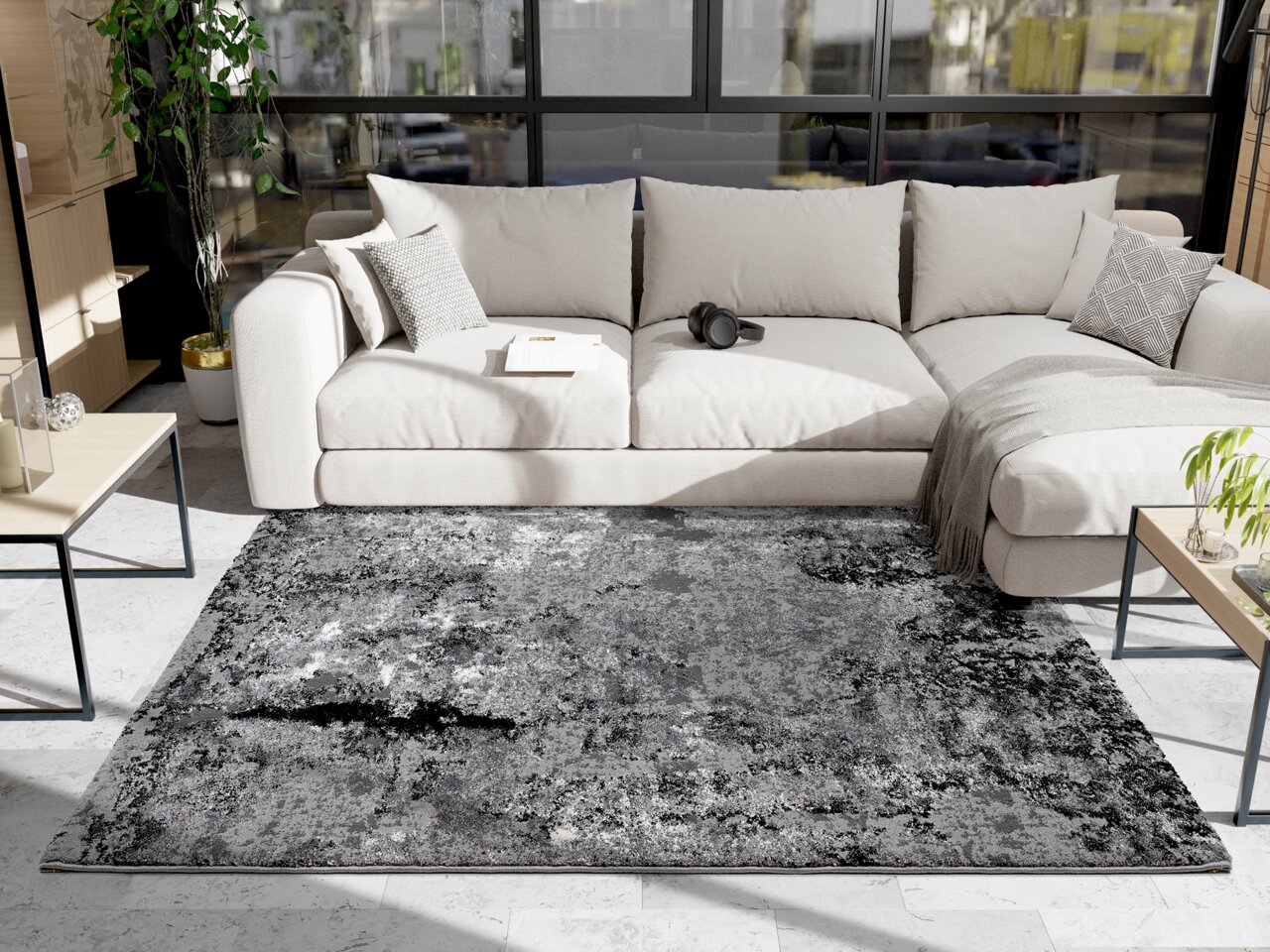 Moderner Wohnzimmerteppich in Grautönen vor einem beigen Sofa, fotografiert aus einer leicht erhöhten Perspektive.