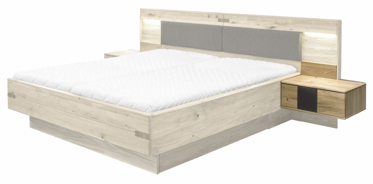 Linea Natura Nachtkonsole rechts TABILO Nachtkonsole rechts in Holzoptik, perspektivisch von vorne rechts gesehen, neben einem Bett mit gepolstertem Kopfteil.