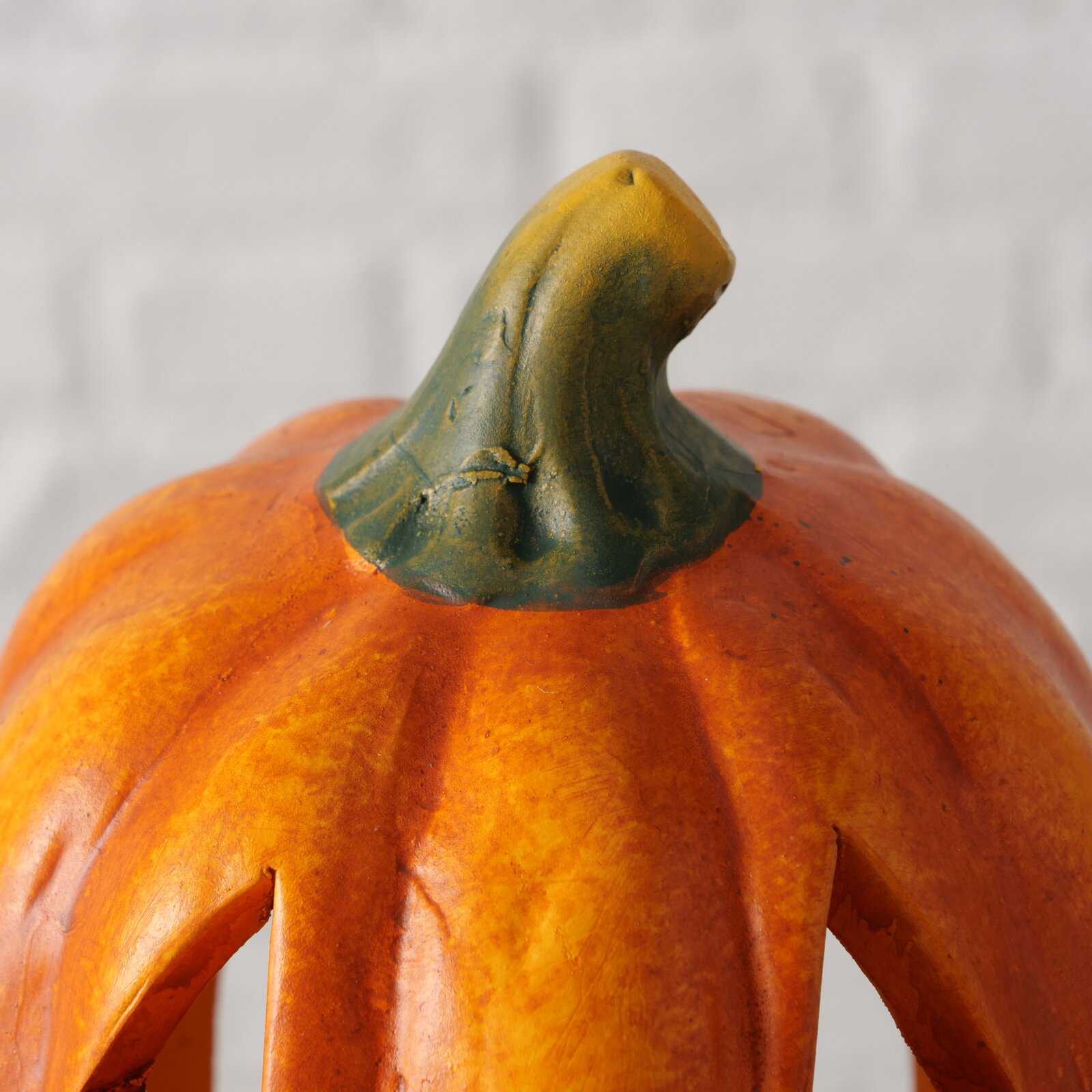 Nahaufnahme eines Teelichthalters in Form eines Kürbisses mit grünem Stiel, von oben betrachtet.