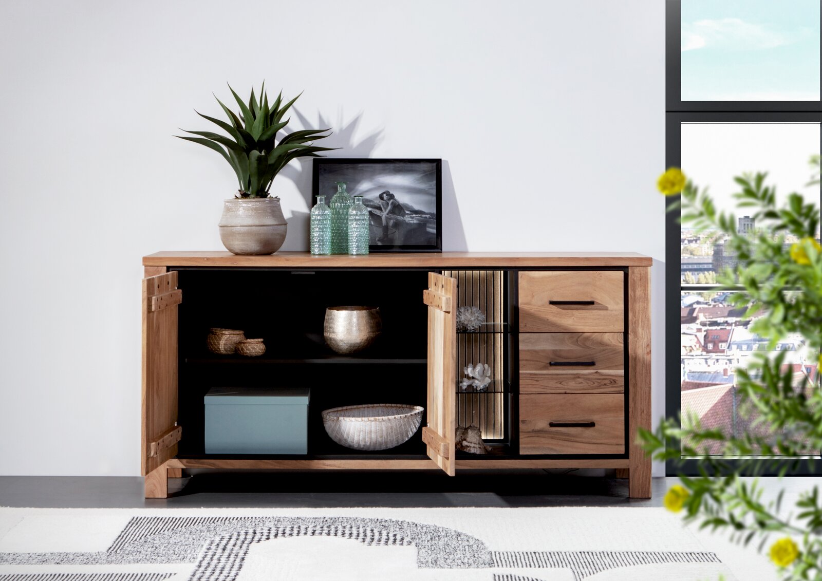 Holz-Sideboard mit geöffneter Tür, dekoriert mit Pflanzen und Accessoires, seitliche Perspektive