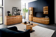 Moderne Wohnzimmermöbelkombination in Holzoptik mit LED-Beleuchtung, bestehend aus Sideboard, Highboard, Couchtisch und TV-Element, aus der Perspektive eines gemütlichen Wohnzimmers.