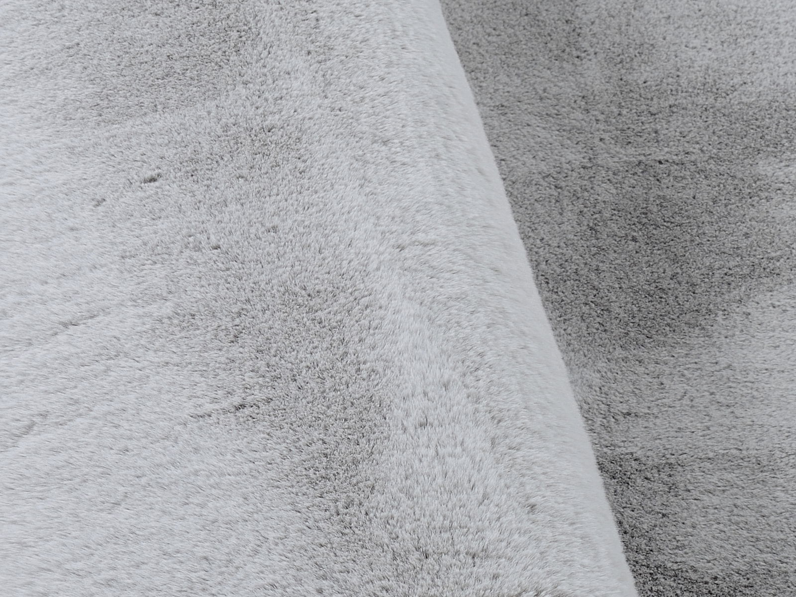 Nahaufnahme eines grauen, weichen Fellteppichs mit flauschiger Textur.