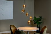 Moderne Hängeleuchte mit fünf kugelförmigen, transparenten Lampenschirmen, die in einem eleganten Esszimmer über einem runden Tisch hängen. Seitliche Perspektive.