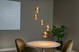 Moderne Hängeleuchte mit fünf kugelförmigen, transparenten Lampenschirmen, die in einem eleganten Esszimmer über einem runden Tisch hängen. Seitliche Perspektive.