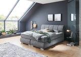 Gemütliches Boxspringbett in modernem Schlafzimmer mit Dachschräge, seitliche Perspektive