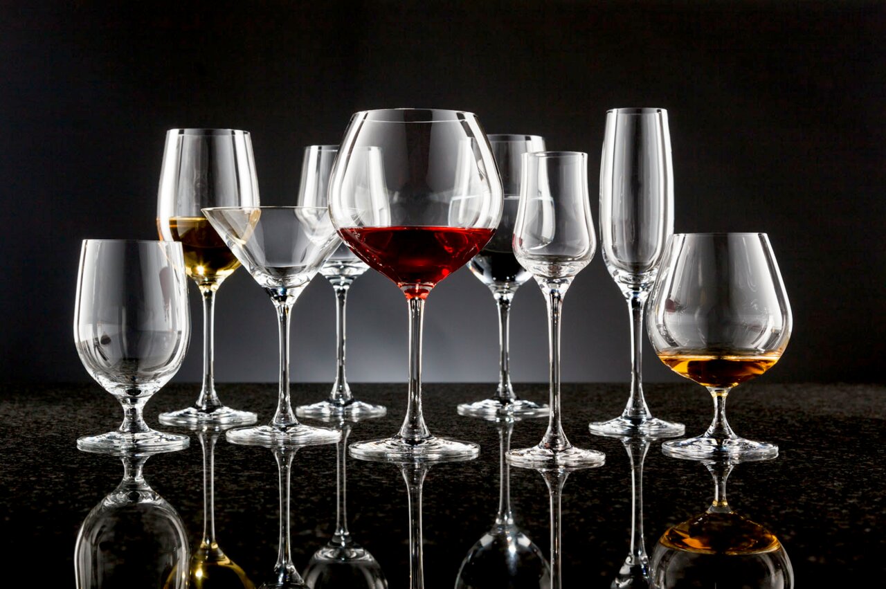 Verschiedene Ciao+ Gläser auf einer reflektierenden Oberfläche, frontal betrachtet.