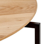 Nahaufnahme eines Couchtischs mit runder Holzplatte und schwarzem Metallgestell, seitliche Perspektive