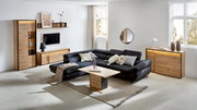 Modernes Wohnzimmer mit einem schwarzen Ecksofa, einem Couchtisch aus Holz und Metall, einem TV-Lowboard, einem Highboard und einer Kommode aus Holz. Die Möbel sind in einem hellen Raum mit großen Fenstern und minimalistischer Dekoration platziert. Perspe