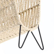 Nahaufnahme eines geflochtenen Zeitungsständers mit schwarzem Metallgestell, seitliche Perspektive