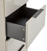 Geöffnete Schublade eines modernen weißen Schranks mit schwarzem Innenraum und Griffleiste, Detailaufnahme in schräger Seitenansicht von vorne