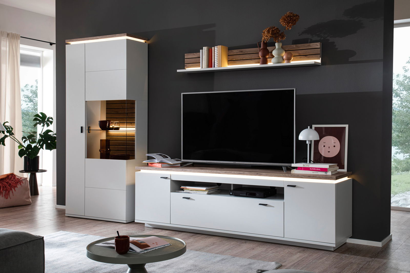 Stylife Wandkombination mit Beleuchtung ESTEPONA Moderne Wohnwandkombination mit LED-Beleuchtung, bestehend aus Highboard, TV-Board und Wandregal, in einer stilvollen Wohnzimmerumgebung. Frontalansicht.