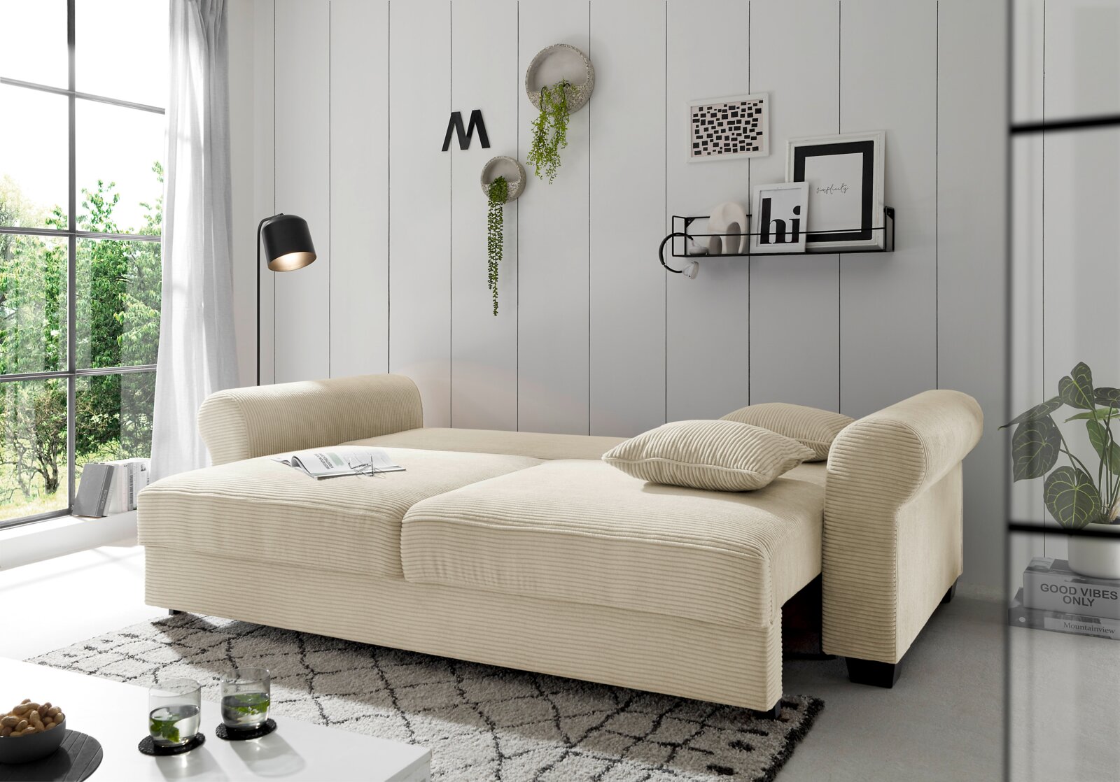 Beige functionele bank in een moderne woonkamer, gezien vanaf de zijkant, met kussens en decoratieve elementen.