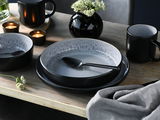 Elegantes Kombiservice 30-tlg. Frost in Schwarz und Grau, bestehend aus Tellern, Schalen und Tassen, auf einem Holztisch mit Kerzen und Blumen, aus der Vogelperspektive fotografiert.