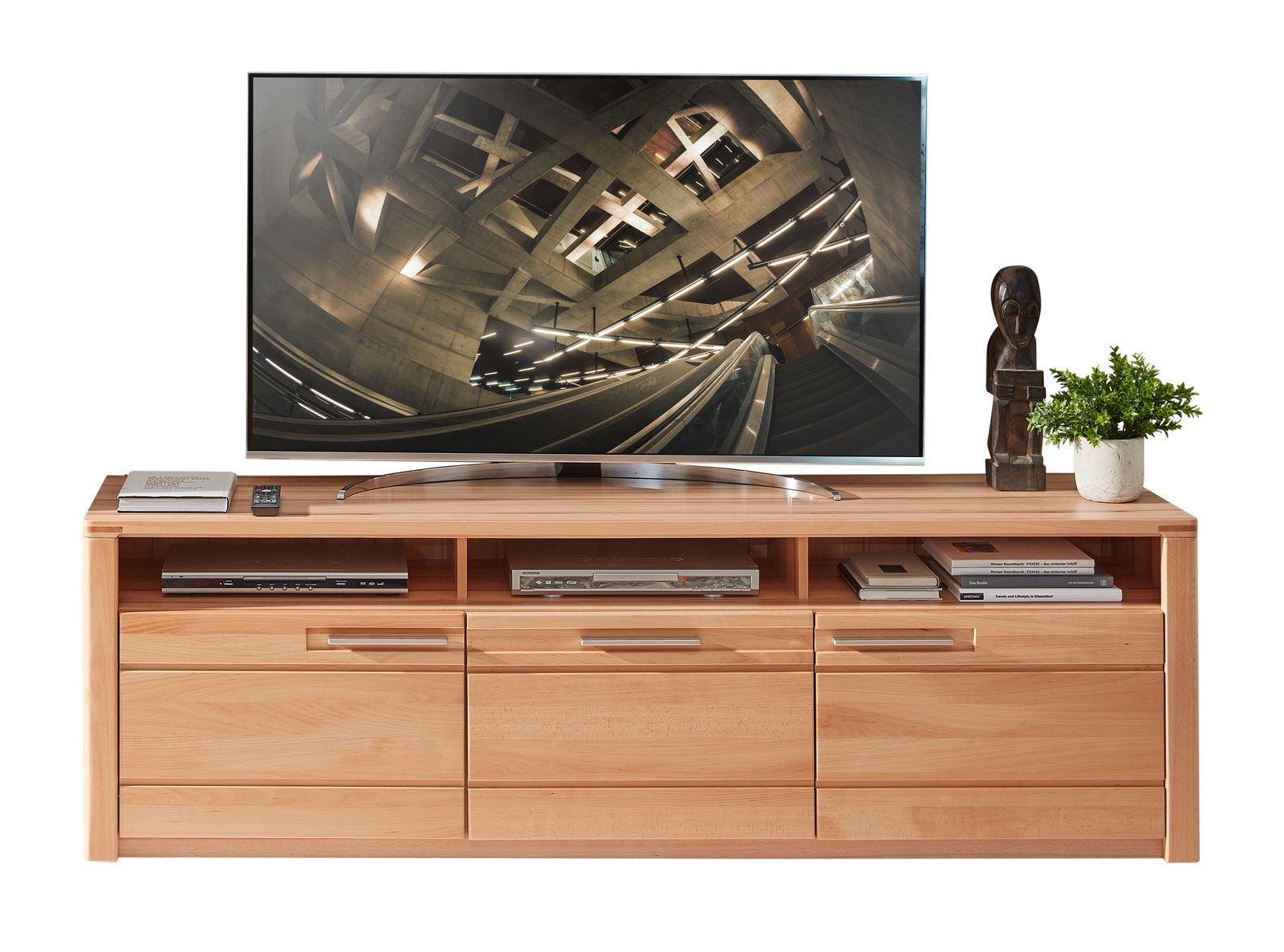 Frontale Ansicht eines TV-Lowboards aus Holz mit mehreren Schubladen und offenen Fächern, dekoriert mit Büchern, einer Skulptur und einer Pflanze, darauf steht ein großer Flachbildfernseher.