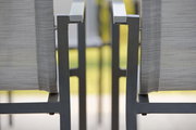 Nahaufnahme von zwei grauen Stapelsesseln aus Metall mit Armlehnen, seitliche Perspektive.