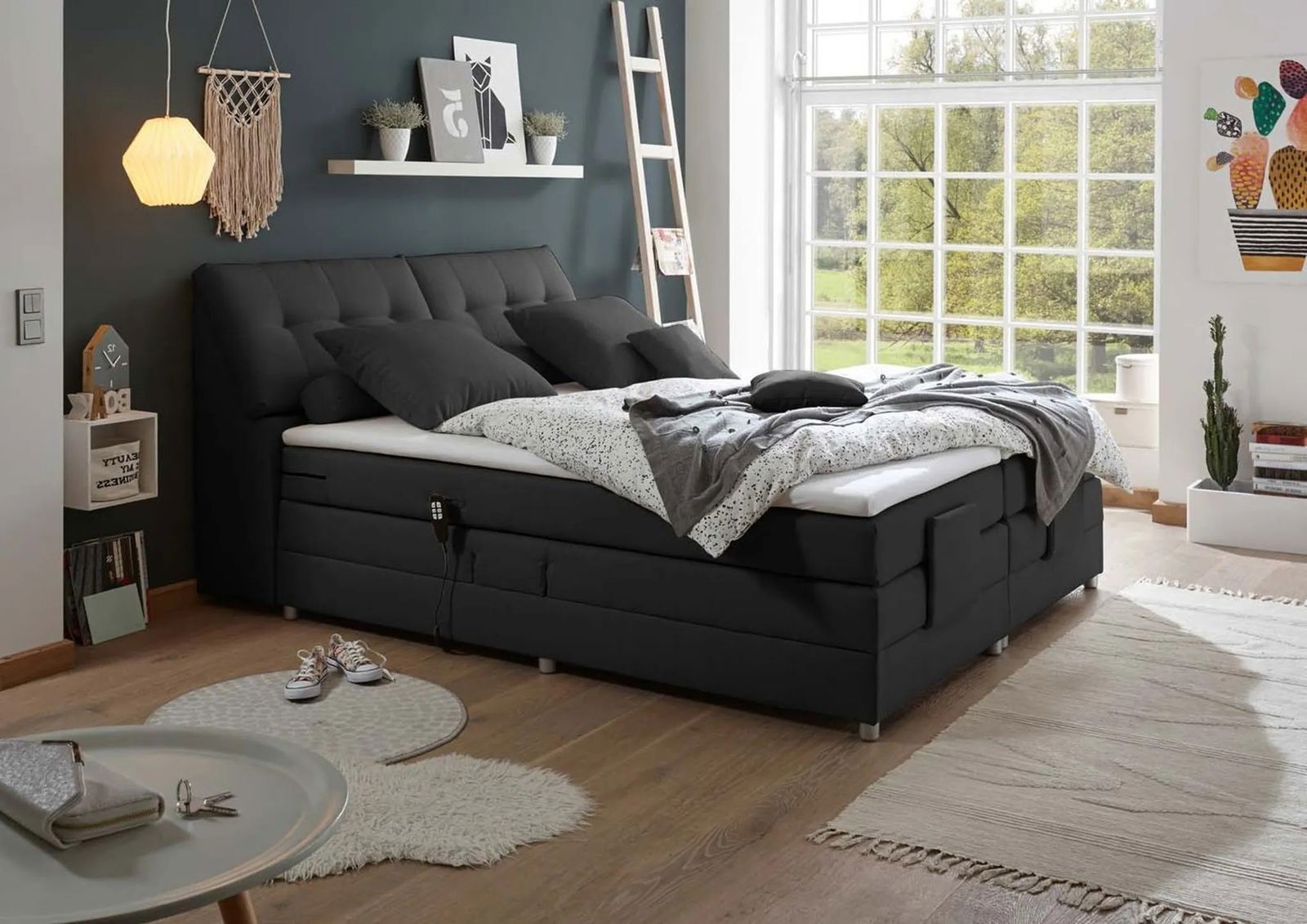 Modernes Boxspringbett in einem stilvollen Schlafzimmer mit Blick auf ein großes Fenster, das Tageslicht hereinlässt.